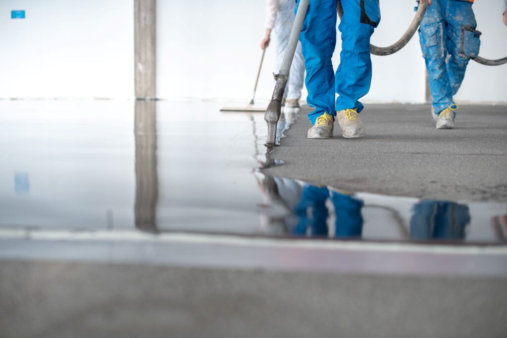 Polished Concrete vs. Epoxy Coatings: Which Is Right for Your Commercial Floor? 1 construction workers leveling flooring in modern b 2026 03 16 04 29 26 utc